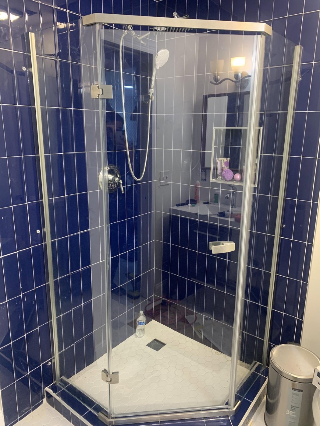 Frameless glass door installed on a navy tiled walk-in shower